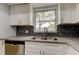 Updated kitchen with white cabinets, granite counters, stainless steel sink, and sleek dark backsplash for a modern touch at 1466 Normandy Park Dr # 4, Clearwater, FL 33756