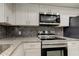 Well-equipped kitchen featuring stainless steel appliances, granite countertops, white cabinetry, and dark subway tile backsplash at 1466 Normandy Park Dr # 4, Clearwater, FL 33756