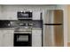Contemporary kitchen featuring stainless steel appliances, granite countertops, white cabinetry, and dark subway tile at 1466 Normandy Park Dr # 4, Clearwater, FL 33756