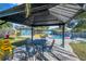 Cozy outdoor patio with table and seating overlooking a landscaped backyard with pool at 1571 Belleair Rd, Clearwater, FL 33756