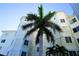 Exterior angle shot of cream and white condominium building with a red tile roof and a palm tree in front of it at 1860 N Fort Harrison Ave # 301, Clearwater, FL 33755
