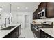 Well-equipped kitchen featuring stainless steel appliances, quartz countertops, dark cabinets, and modern fixtures at 22229 Storybook Cabin Way, Land O Lakes, FL 34637