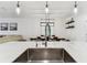 Bright kitchen sink view toward dining area with farmhouse table and modern light fixtures and floating shelves at 22229 Storybook Cabin Way, Land O Lakes, FL 34637