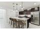 Modern kitchen with a marble waterfall island, stainless steel appliances, dark cabinets, and stylish pendant lighting at 22229 Storybook Cabin Way, Land O Lakes, FL 34637