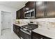 Kitchen featuring stainless steel gas range, dark cabinetry, quartz counters, and modern backsplash tile at 22229 Storybook Cabin Way, Land O Lakes, FL 34637