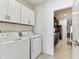 Bright laundry room with white washer, dryer and overhead cabinets next to the kitchen for easy multi-tasking at 22229 Storybook Cabin Way, Land O Lakes, FL 34637