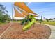 Community playground with a slide and various play structures, partially shaded for a comfortable experience at 22229 Storybook Cabin Way, Land O Lakes, FL 34637