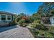 Well-manicured backyard with brick paver patio, lush gardens, and charming outdoor shed at 223 Lime S Cir, Dunedin, FL 34698