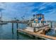 A boat is seen docked in a marina on a sunny day with beautiful blue skies and palm trees at 223 Lime S Cir, Dunedin, FL 34698
