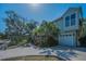 Charming home with a two-car garage and a beautifully landscaped front yard, featuring mature trees and a well-maintained lawn at 223 Lime S Cir, Dunedin, FL 34698
