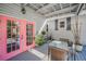 Charming covered patio with outdoor dining, and vibrant pink french doors at 223 Lime S Cir, Dunedin, FL 34698