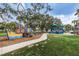 Community playground with slides, swings, and climbing structures, surrounded by lush greenery and mature trees at 223 Lime S Cir, Dunedin, FL 34698