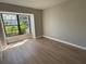 Bright bedroom with light wood flooring, a large window with green foliage, and neutral paint at 2571 Cyprus Dr # 1-102, Palm Harbor, FL 34684