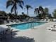 Community pool with lounge chairs, palm trees, and secured by a white fence at 2571 Cyprus Dr # 1-102, Palm Harbor, FL 34684