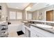 Bright bathroom featuring double sinks, granite countertops, white cabinetry, soaking tub, and plantation shutters at 2837 Bayshore Trails Dr, Tampa, FL 33611