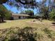 Expansive backyard featuring a green lawn, mature trees, patio seating, and partially shaded areas at 3257 Bluestone Ave, Spring Hill, FL 34609
