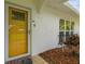 Close-up of the bright yellow front door featuring textured walls and manicured plants adding curb appeal at 4555 Debbie Ln, Lutz, FL 33559