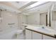 Bright bathroom with a tiled shower, tub, grab bars, and a large mirror at 5245 Lochmead Ter, Zephyrhills, FL 33541