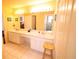 Bright bathroom featuring a long vanity with dual sinks and Hollywood lights at 7345 Brightwaters Ct, New Port Richey, FL 34652