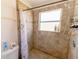 Tiled shower with shower head, toiletry rack, and window with toiletries at 7345 Brightwaters Ct, New Port Richey, FL 34652