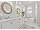 Bright bathroom with dual sinks, marble countertops, a modern bathtub, and decorative shelving at 7417 S Morton St, Tampa, FL 33616