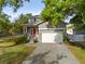 Charming two-story home with a red front door, a brick paved driveway, and a two-car garage at 7417 S Morton St, Tampa, FL 33616