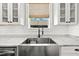 Close-up of stainless steel farmhouse sink with spring faucet, marble countertops, and white cabinets at 7417 S Morton St, Tampa, FL 33616
