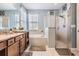 Bright bathroom featuring a double vanity with granite counters, tub, and glass shower at 8247 Westhaven Dr, Land O Lakes, FL 34638