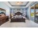 Bedroom with tray ceiling, a dark wood sleigh bed, light carpet, and sliding doors to the lanai at 8247 Westhaven Dr, Land O Lakes, FL 34638