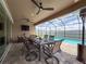 Enclosed lanai area overlooking the pool has an outdoor dining table, TV, and comfortable seating at 8578 Gibbons Grove Loop, Land O Lakes, FL 34637