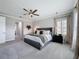 Spacious carpeted main bedroom with a ceiling fan, large bed and plantation shutters at 8578 Gibbons Grove Loop, Land O Lakes, FL 34637