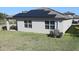 Rear view of home with solar panels, grassy lawn, two double-hung windows, and HVAC unit at 901 Golden Shiner Ave, Ruskin, FL 33570