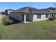 A backyard featuring a lush green lawn, stucco wall, and solar panels on the roof of the home at 901 Golden Shiner Ave, Ruskin, FL 33570