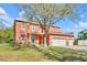 Two-story orange home with large tree and lawn, decorative stone accents and attached two-car garage at 9102 Kentucky Day Ct, Gibsonton, FL 33534