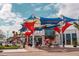 Vibrant town center featuring colorful awnings and outdoor seating, surrounded by lush greenery and modern architecture at 18057 Foxtail Loop, Venice, FL 34293