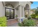 Elegant home exterior with decorative glass front doors, stone columns, manicured landscaping and brick walkway at 21654 Draycott Way, Land O Lakes, FL 34637