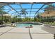 A refreshing screened pool with jacuzzi surrounded by lounge chairs, shade umbrellas and green backyard at 21654 Draycott Way, Land O Lakes, FL 34637