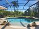 A stunning screened pool with a jacuzzi is surrounded by lush greenery, rocks and potted plants at 21654 Draycott Way, Land O Lakes, FL 34637