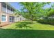 Lush green backyard featuring a row of townhomes and mature trees, creating a tranquil environment at 2211 Kings Palace Dr, Riverview, FL 33578