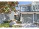 Close up of the townhome featuring a one-car garage, neutral paint, and mature trees providing shade at 2211 Kings Palace Dr, Riverview, FL 33578