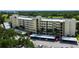 Aerial view of the condo building with a covered parking area and tropical trees at 225 Country Club Dr # 1104, Largo, FL 33771