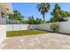 View of the backyard featuring a white privacy fence and a brick paver patio with palm trees in the background at 331 Barbara Cir, Belleair, FL 33756