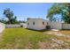 Backyard featuring a white privacy fence, lush green grass, an AC unit and the exterior of the home at 331 Barbara Cir, Belleair, FL 33756