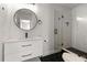 Modern bathroom showcasing a stylish vanity, round mirror, and a sleek glass-enclosed shower with black accents at 331 Barbara Cir, Belleair, FL 33756