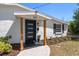 Close up of home's modern entrance features a new black door and stylish wooden supports at 331 Barbara Cir, Belleair, FL 33756