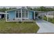 Attractive light blue home boasting lush landscaping, covered parking, and a welcoming front porch at 35026 Colony Hills Dr, Zephyrhills, FL 33541