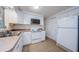 A kitchen featuring white cabinets, laminate countertops and tile flooring with an oven, microwave and refrigerator at 3815 Bowen St, New Port Richey, FL 34652