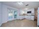 Well-lit kitchen adjacent to a sunroom, featuring white appliances, efficient cabinetry, and neutral tile flooring at 3815 Bowen St, New Port Richey, FL 34652