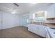 Bright kitchen with white cabinets, tile flooring, double-basin sink and access to the patio through glass doors at 3815 Bowen St, New Port Richey, FL 34652