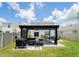 Backyard with a pergola featuring grilling area, a hammock, an outdoor dining set, and lush green grass at 5571 Birch River Trl, Wesley Chapel, FL 33545